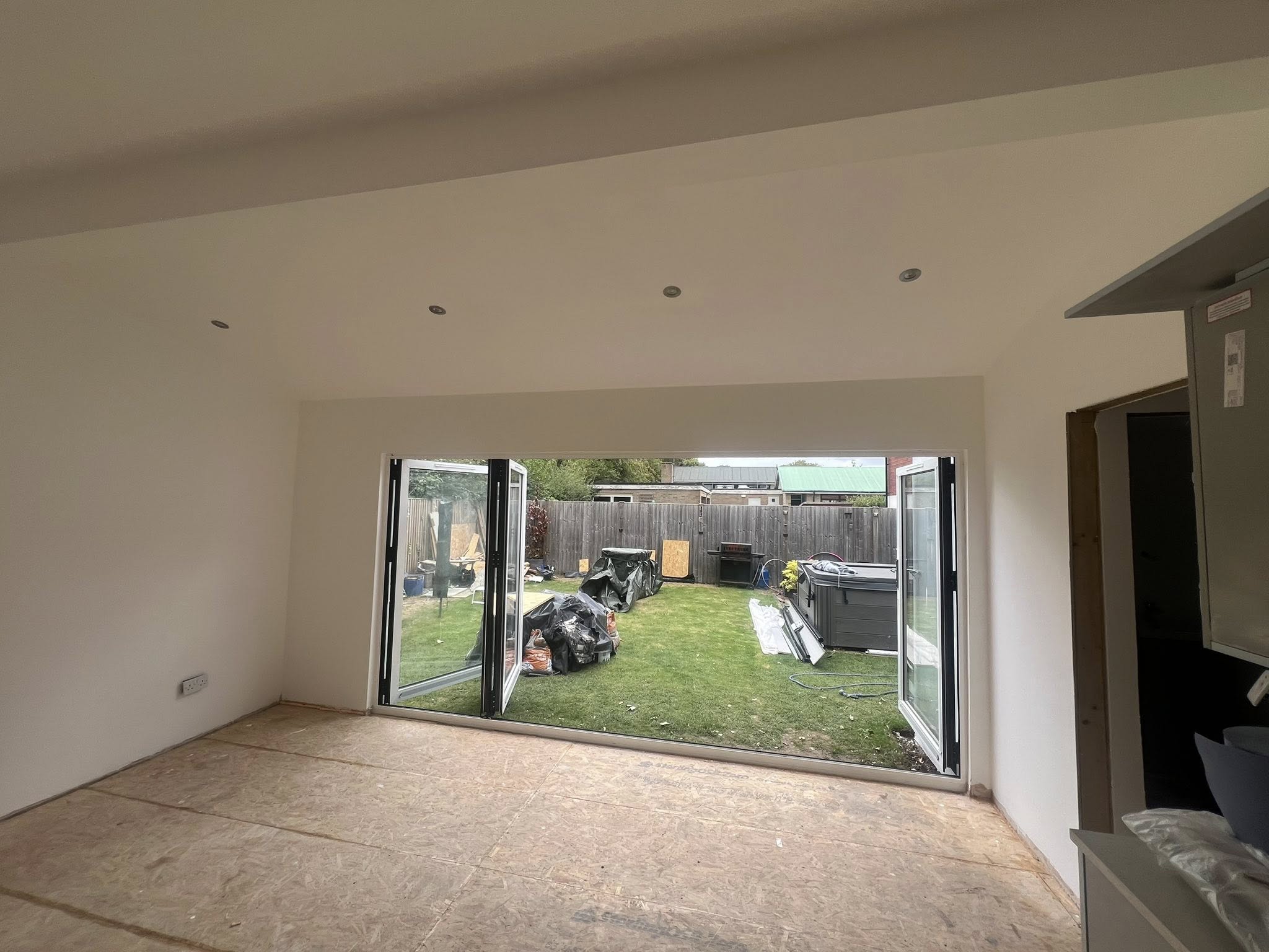 Vaulted extension interior with open bi-fold doors to garden